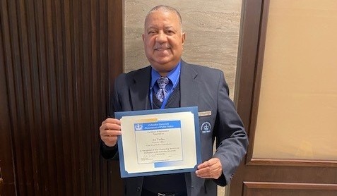 man in a suit holding up perfect attendance certificate