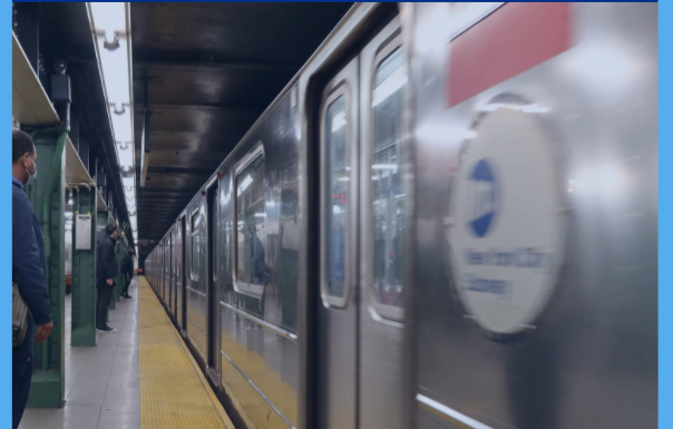 man standing on MTA train platform while train is in station with doors closed