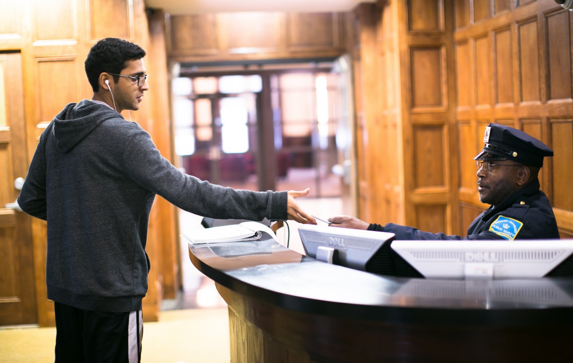 A student handing their ID to a guard at a security desk at a residence hall
