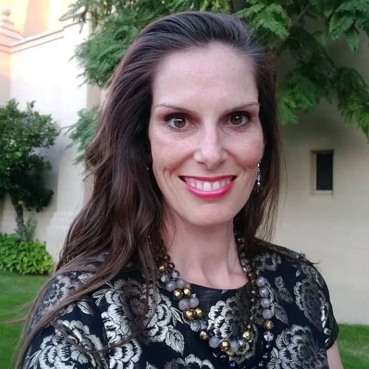 portrait photo of woman with loose brown hair and red lipstick smiling