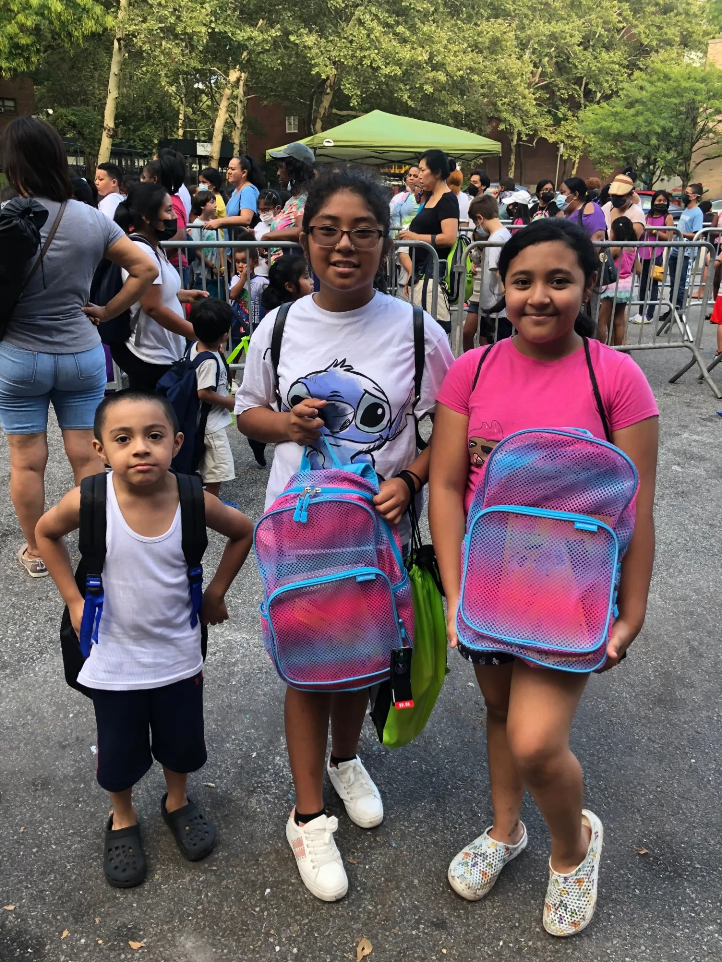 one boy and two girls holding up bookbags