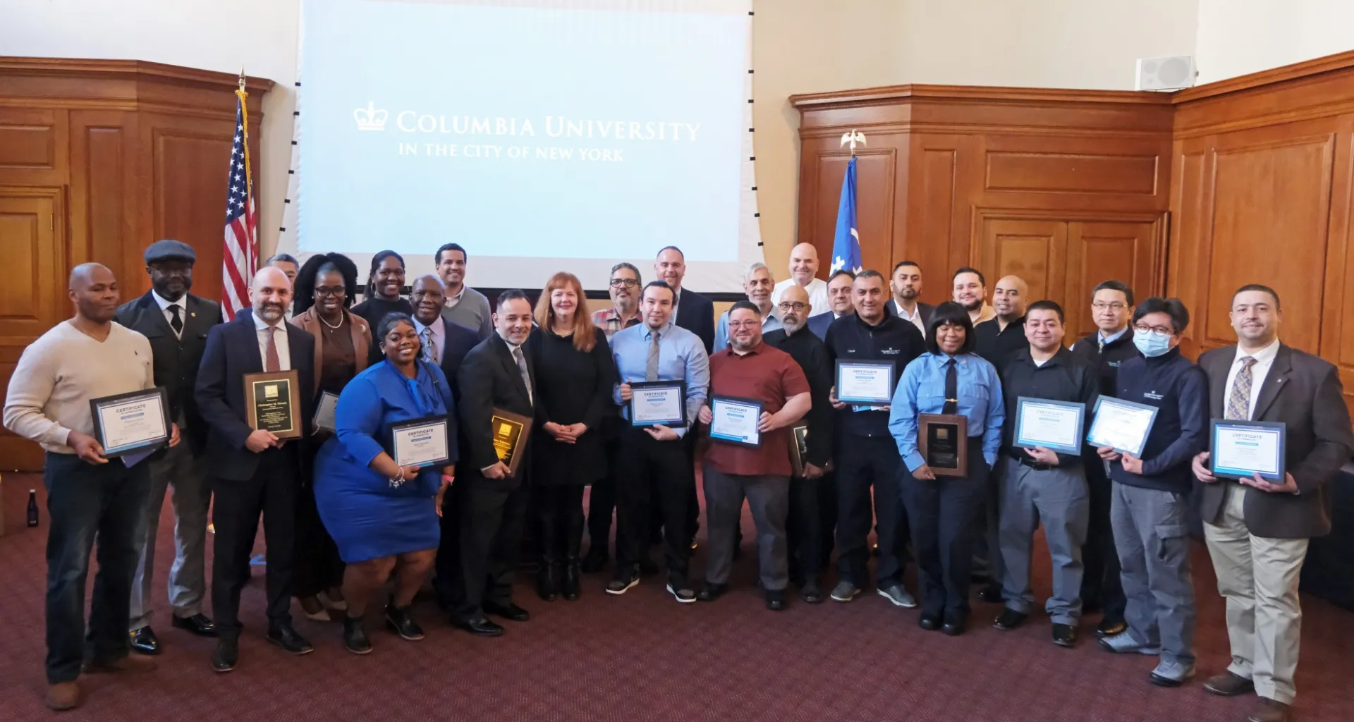 A group of approximately 40 people posing for a photo holding their certificates and plaques